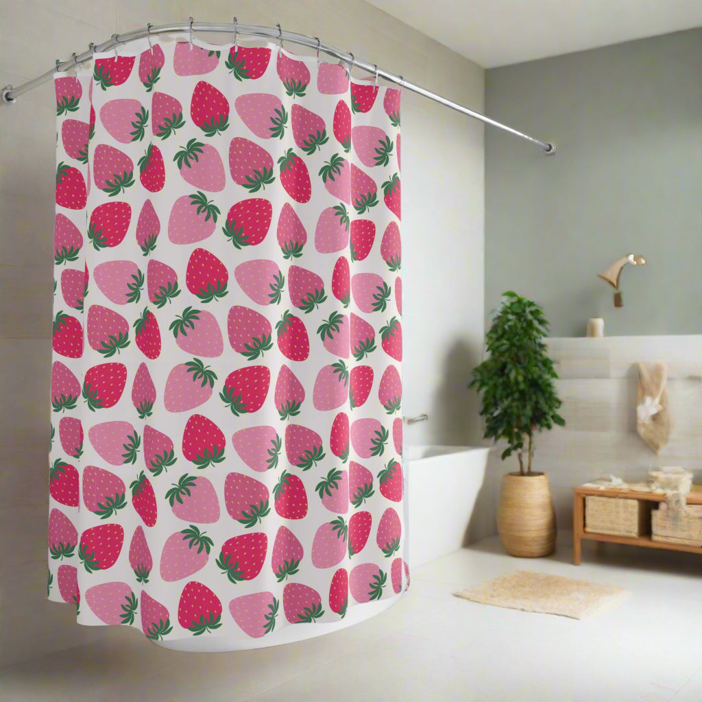A colorful bathroom shower curtain with a fruit theme, displaying orange and pink fruit patterns against a white background, installed in a bathroom with a plant and a wooden stool in the background.