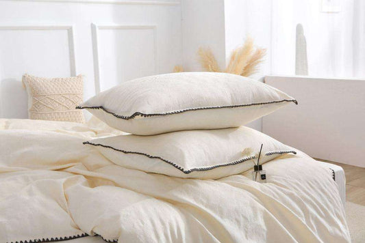 Cream white French vintage duvet cover set on bed with pillows in cozy bedroom.