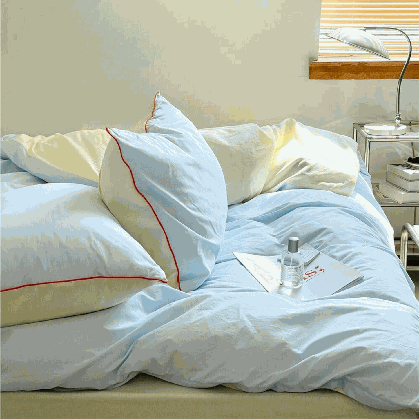 Sky blue and yellow two-tone duvet set with orange piping and matching pillow shams in a bright bedroom setting