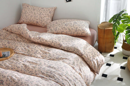 Pink beige duvet cover set with vintage floral print on bed.