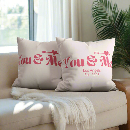 Two white pillows with pink text on a gray couch.