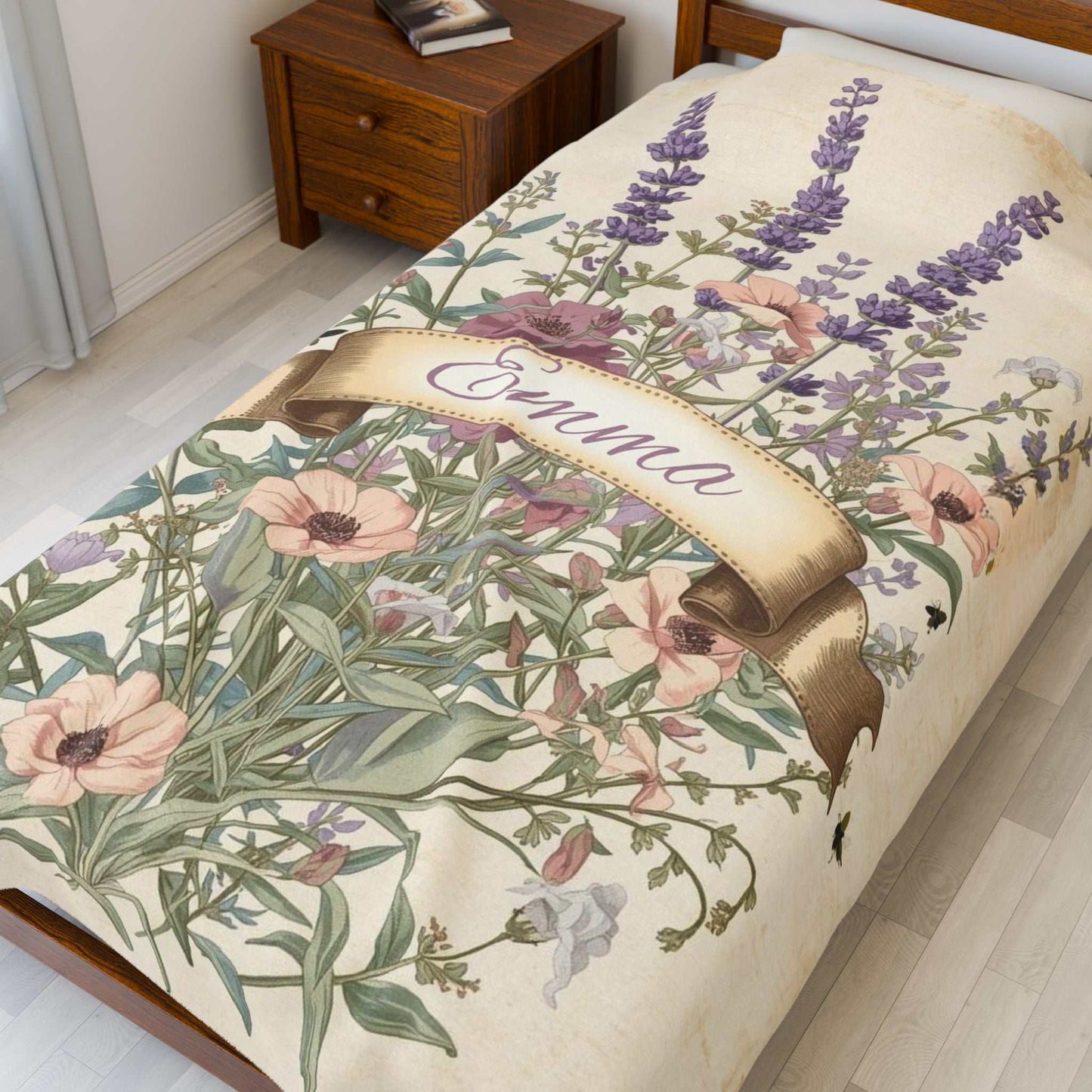 Velveteen plush blanket with floral design and personalized name Emma on bed in cozy room