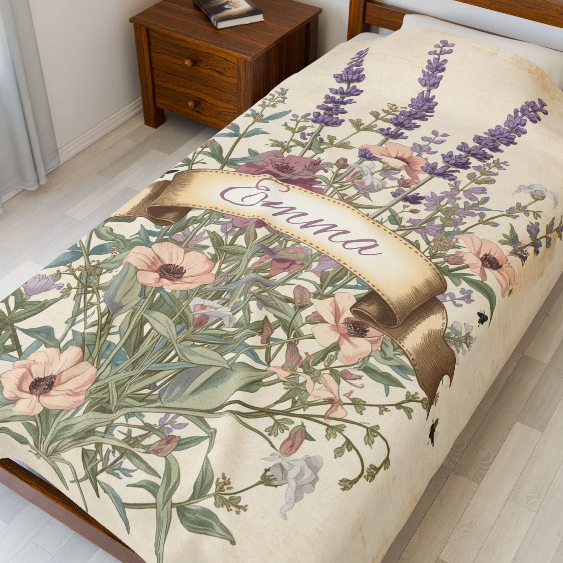 Velveteen plush blanket with floral design and personalized name Emma on bed in cozy room