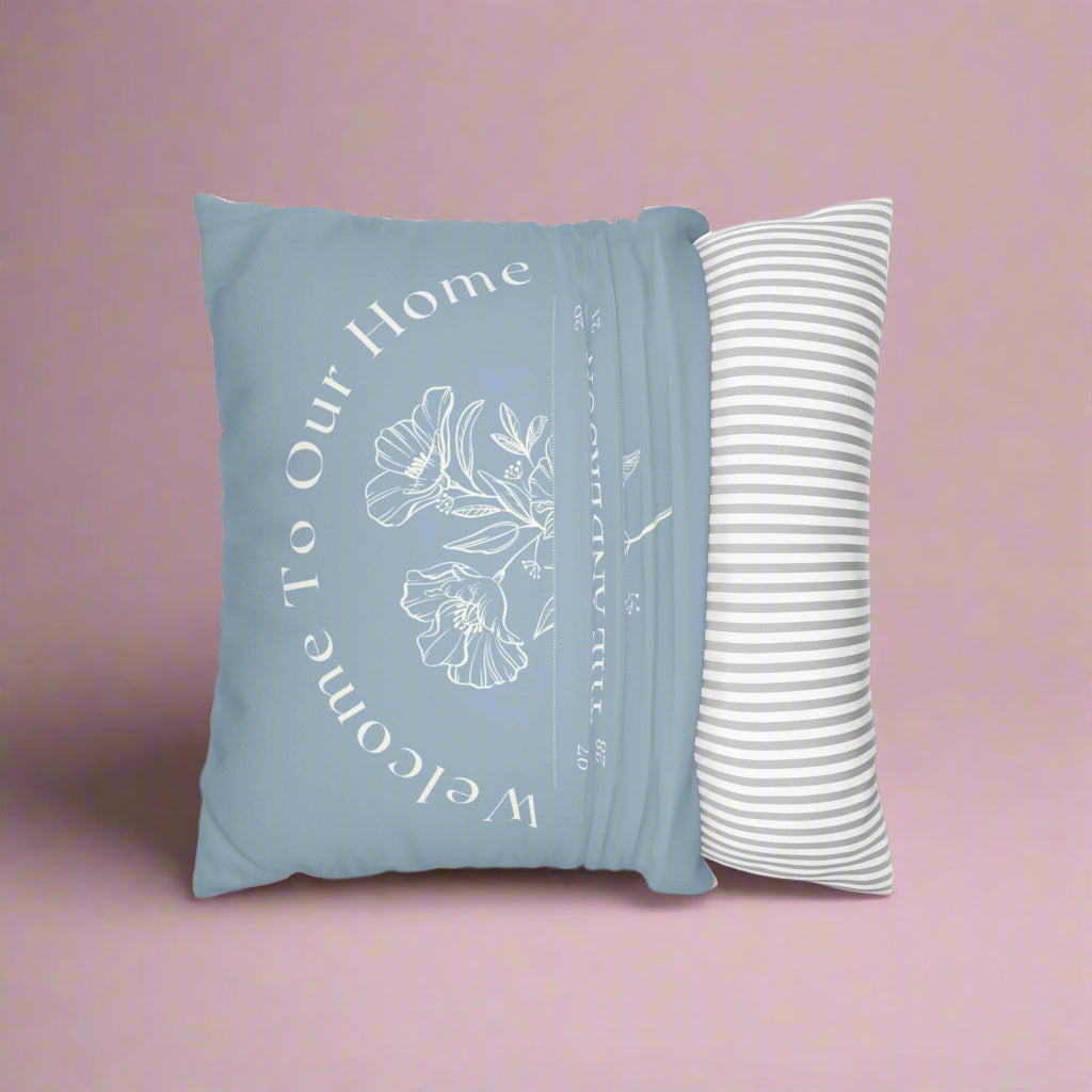 Blue pillow with floral text and white striped pillow on a white background