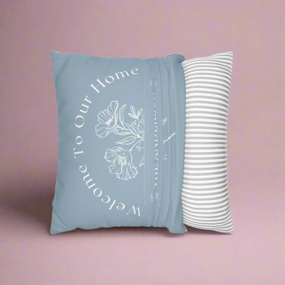Blue pillow with floral text and white striped pillow on a white background