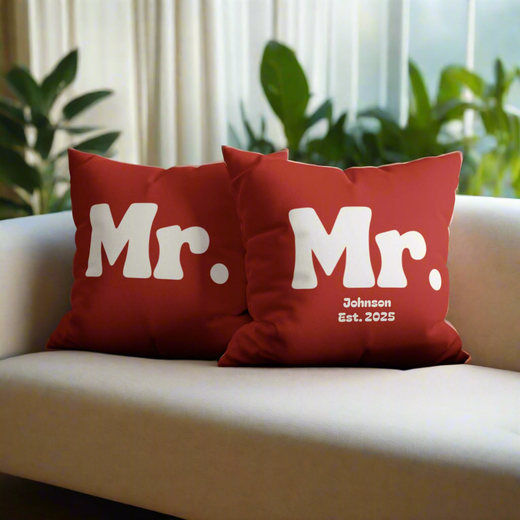 Two red pillows with 'Mr.' text on a gray sofa.
