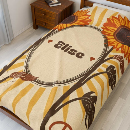 Personalized velveteen plush blanket with sunflower design and custom name "Elise" on cozy bedroom bed