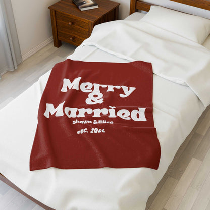 Personalized Christmas blanket in red with white retro "Merry & Married" text, custom names, and established year on bed