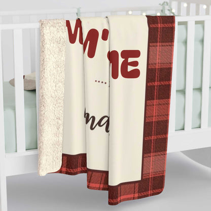 Personalized Mama Bear Christmas blanket with red and black buffalo plaid border draped over white crib, featuring soft fleece material and custom family name design.