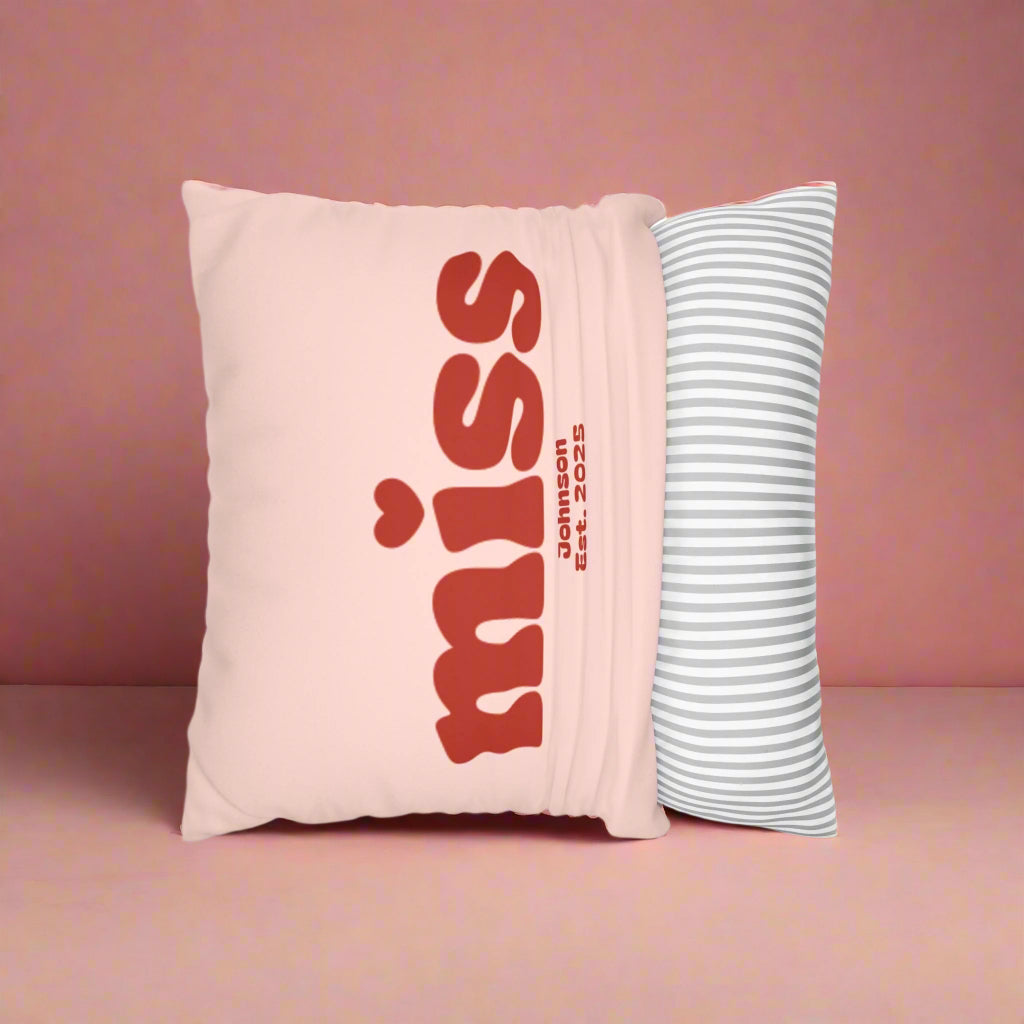 Pink pillow with red text and a striped pillow on a white background