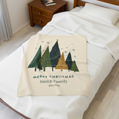 Personalized Christmas family tree fleece blanket with custom family name and holiday design on a bed