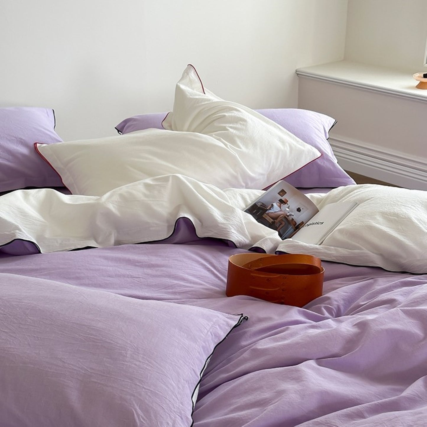  a bed covered with a lilac duvet and white pillows