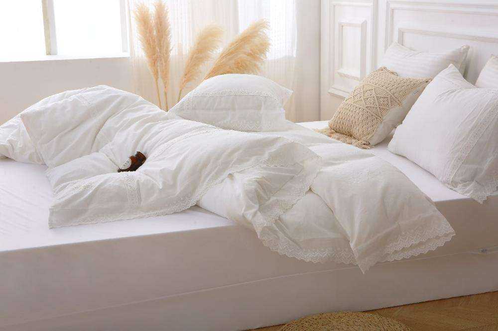 Modern farmhouse duvet cover with lace trim on bed, soft white cotton fabric, elegant bedroom decor.