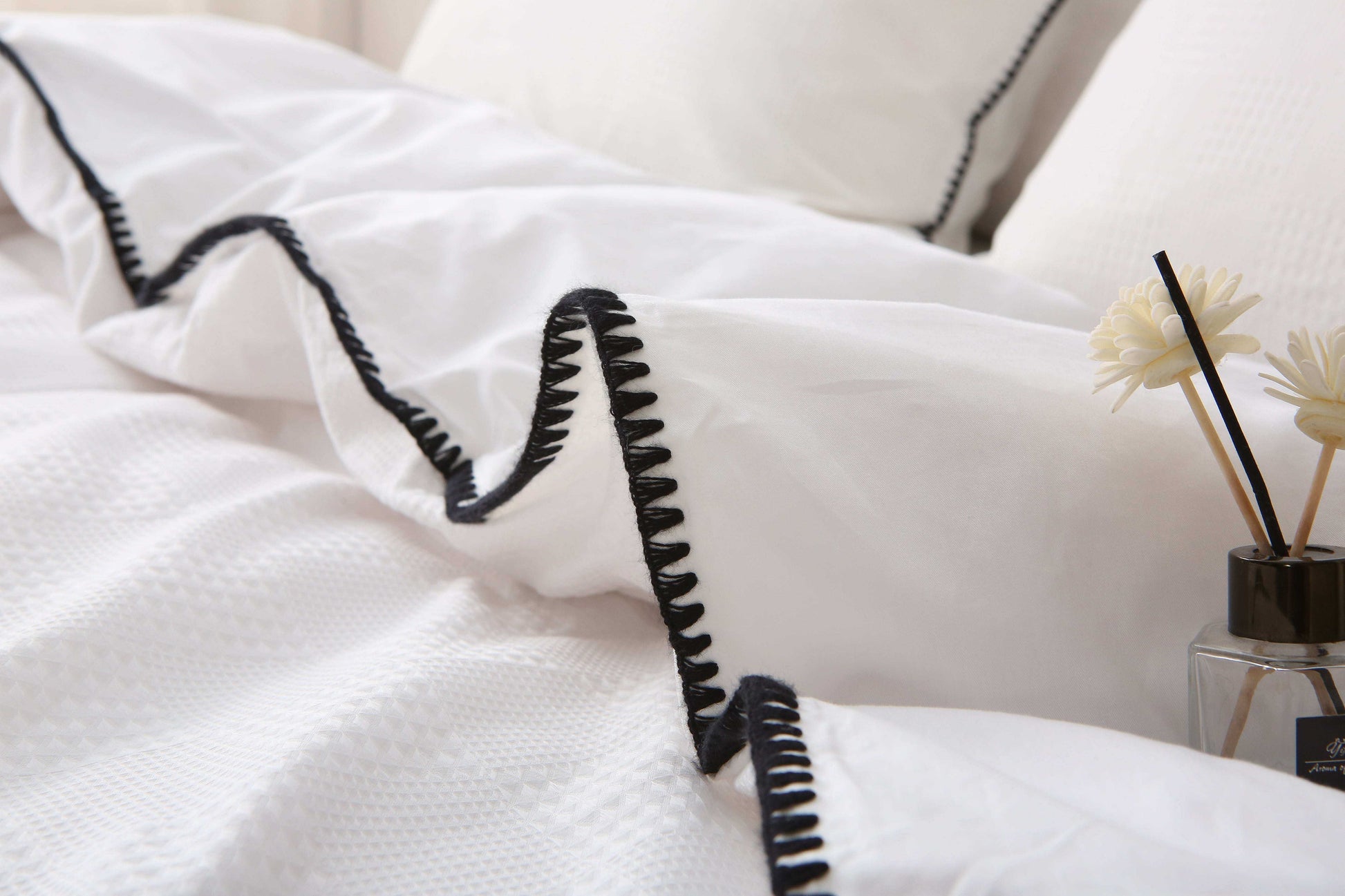 White duvet set with black trim and waffle texture on bed.