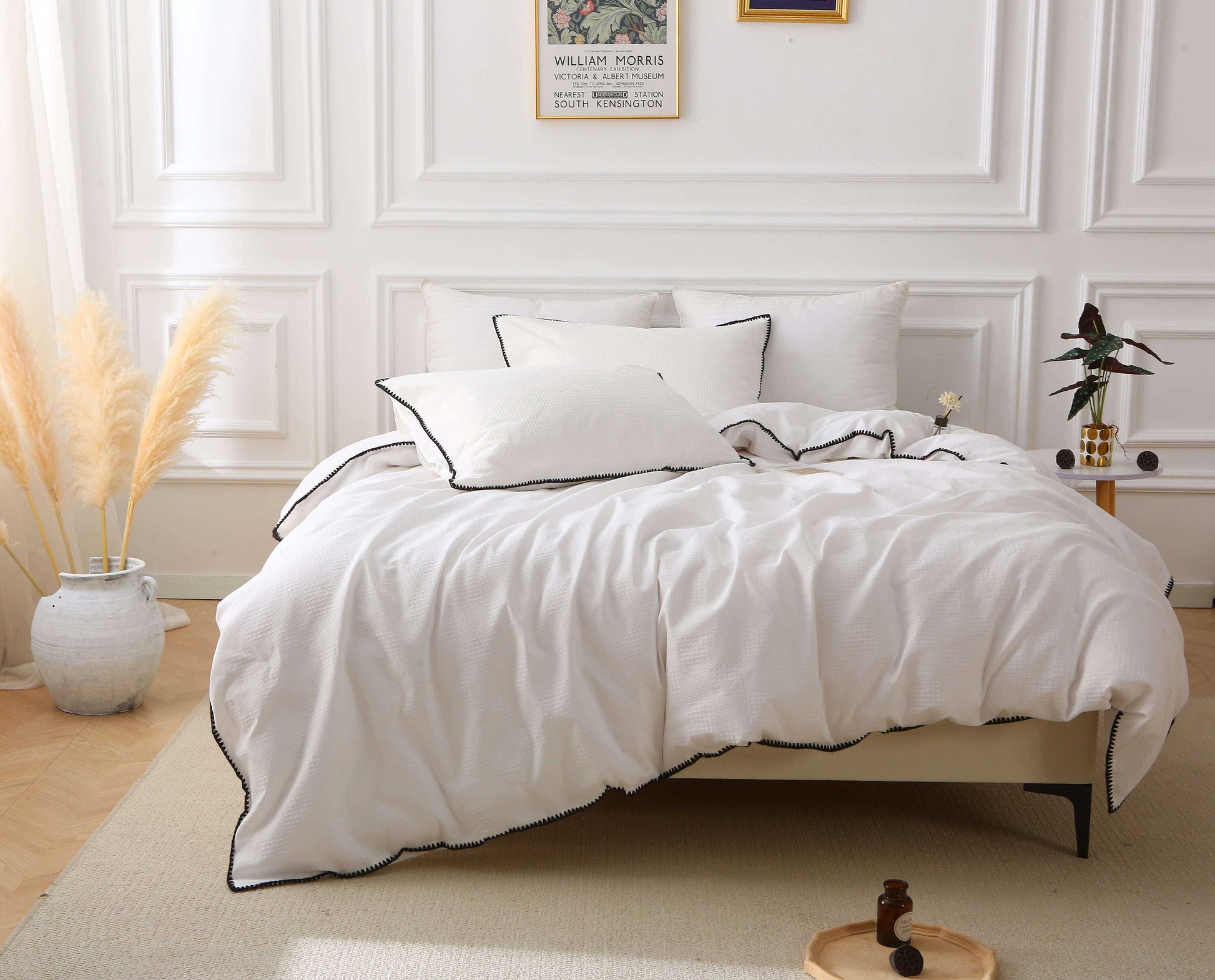 White duvet set with black trim on bed, featuring elegant modern design with waffle texture.