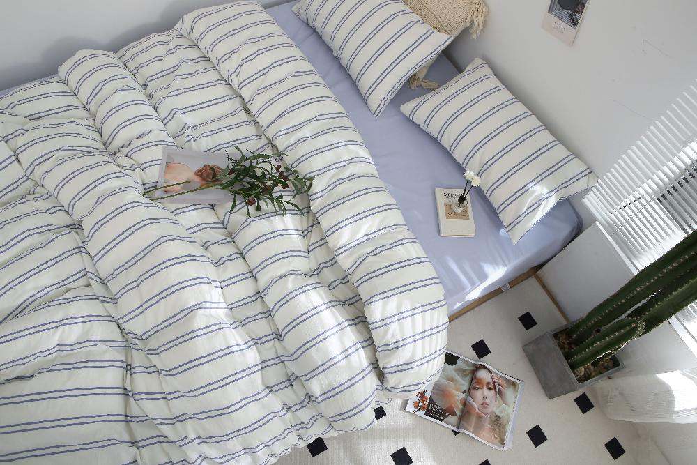 Blue stripe washed cotton bedding set with duvet cover, bed sheet, and pillowcases on a neatly made bed.