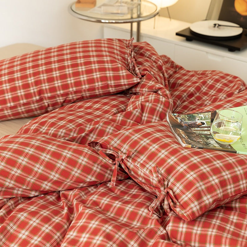 Holiday red plaid duvet cover set with bow tie accents on a bed.