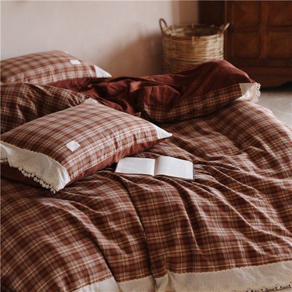 Close up of white lace-trimmed border on a terracotta red plaid cotton fabric.