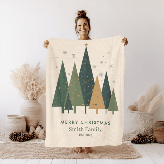 Woman holding a personalized Christmas family tree fleece blanket with green trees and "Merry Christmas Smith Family" text.